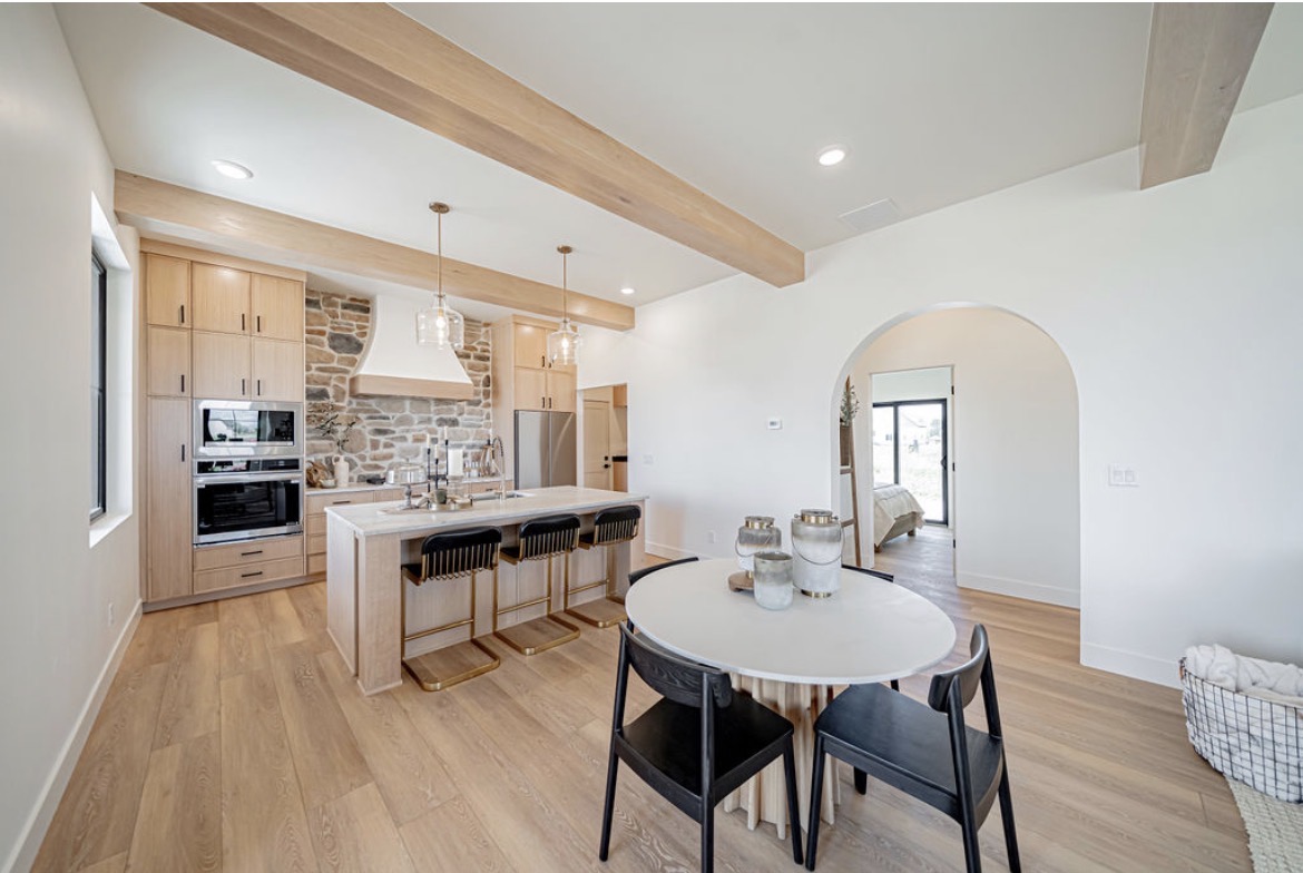 Open kitchen with light oak cabinetry and a plaster range hood