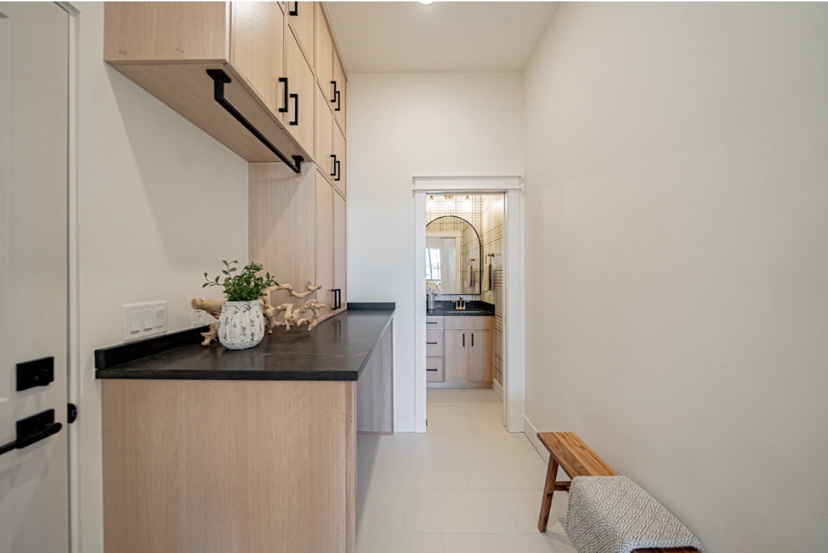 Mudroom counter with dark top and oak cabinetry